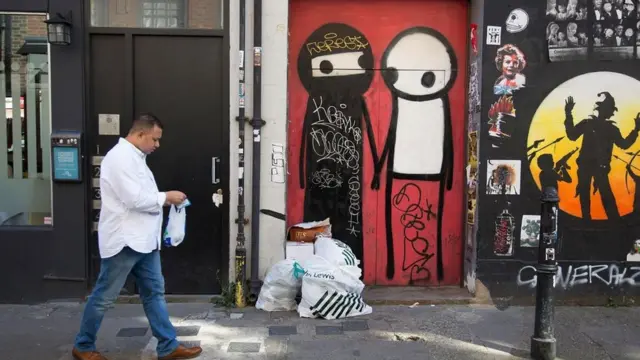 Una persona caminando por una calle llena de distintos grafitis