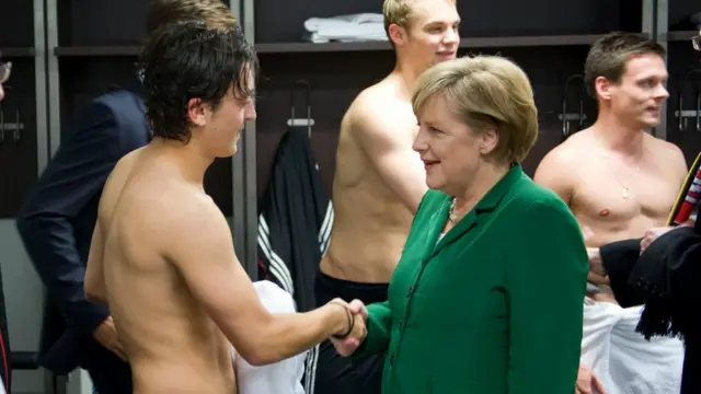 German Chancellor Angela Merkel congratulating Germany"s midfielder Mesut Ozil in the dressing rooms after the Euro 2012