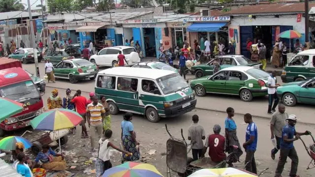 Des taxis, des minicars et de nombreuses personnes dans une rue de Brazzaville.