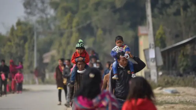 ખભા પર બાળકોને લઈને જતા બે પુરુષ