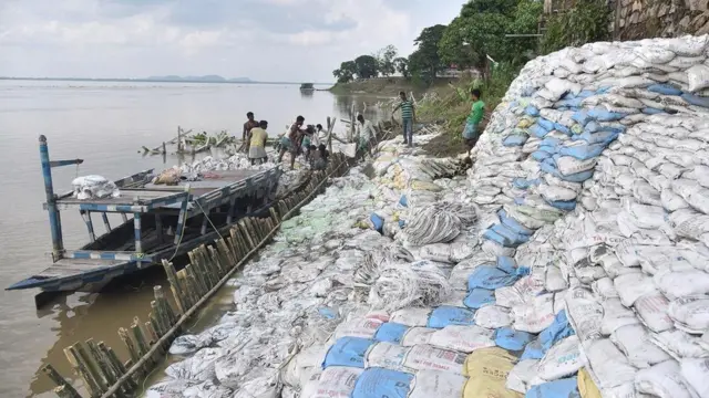 العمال يهيلون أكياس الرمل حماية لضفة البراهمابوترا من النحر عند غواهاتي