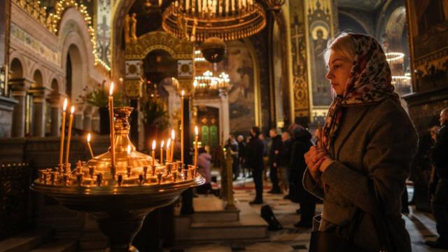 Mulher rezando em igreja na Ucrânia