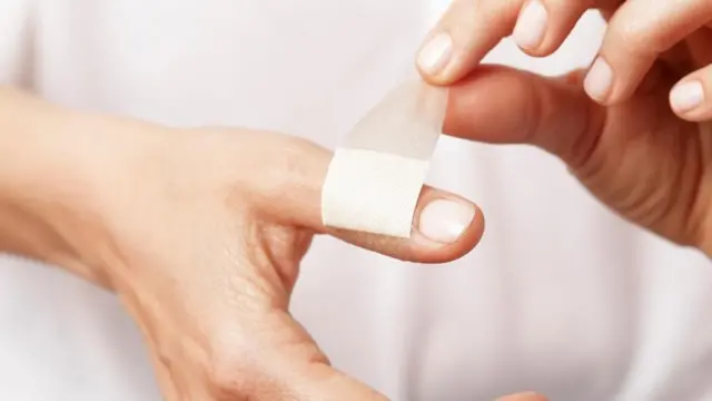 Una persona poniéndose una bandita en un dedo