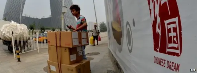 बीजींगमध्ये चायनीज ड्रीमच्या पोस्टरजवळ उभा विक्रेता 6 ऑगस्ट 2013