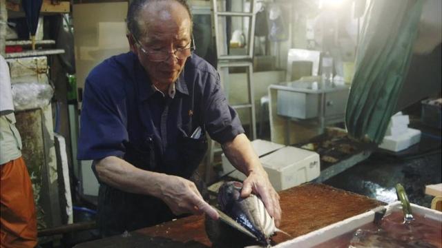 A fishmonger cuts open a fish