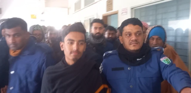 আদালতে কালো চাদর পড়া মাহদী হাসান। তার দুই পাশে পুলিশ সদস্যরা।