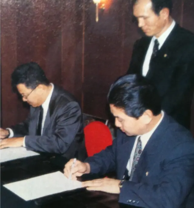 광고사업 계약서에 서명하는 아자커뮤니케이션 박기영 대표와 금강산관광총회사 방종삼 총사장의 뒤에서 지켜보는 박채서