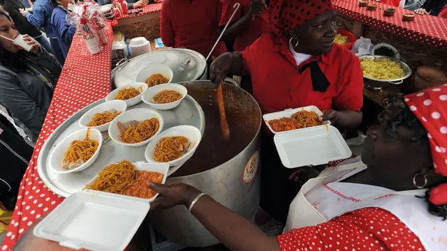 Dos mujeres negras sirven platos en la feria gastronómica mistura