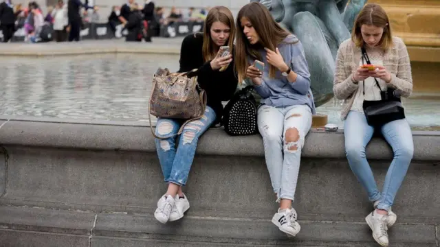 فتيات يستخدمن هواتفهن الذكية