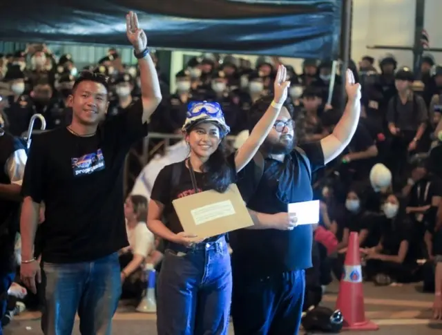 Leaders of pro-democracy protesters Jatupat Boonpattararaksa, aka Pai Dao Din (L) and Patsaravalee Tanakitvibulpon (C) flash the three-finger salute as they hold controversial petition letter over Thai King"s alleged violation of German sovereignty at the German embassy in Bangkok, Thailand, 26 October 2020