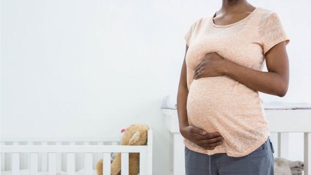 Mulher grávida deixa mãos sobre a barriga