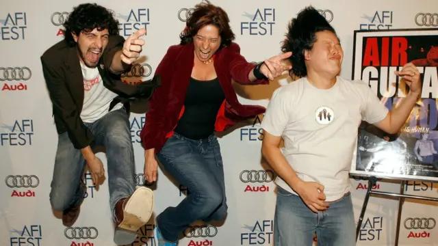 Tres personas tocando "guitarra de aire"