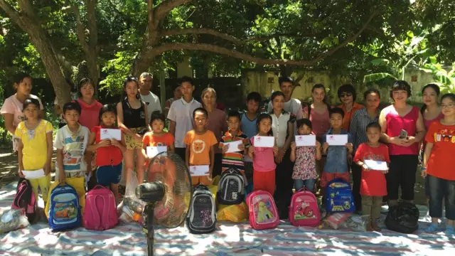 Amie (áo hồng thứ hai hàng trên từ trái) cùng gia đình tặng quà cho trẻ em khó khăn ở Việt Nam hồi 2015