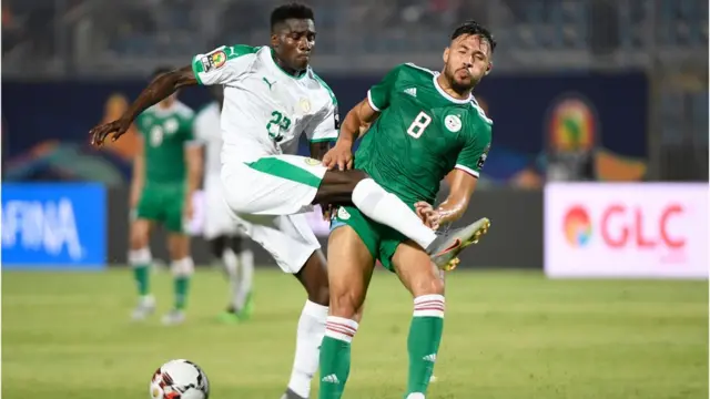 Onye Senegal bụ Moussa Wague (L) na-azọsị onye Algeria bụ Youcef Belaili bọọlụ na Afcon 2019