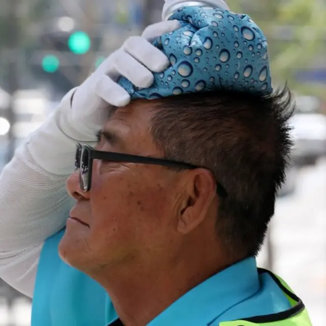 1일 오후 서울 남대문 퇴계로에서 교통정리 자원봉사자가 얼음주머니로 땀을 식히고 있다