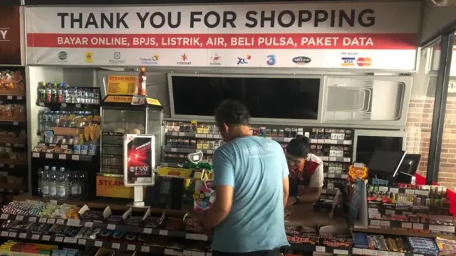 Pelanggan di mini market melakukan pembayaran tunai saat mati lampu.