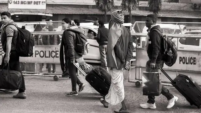 ट्रॉली पर बैग ले जाते यात्री