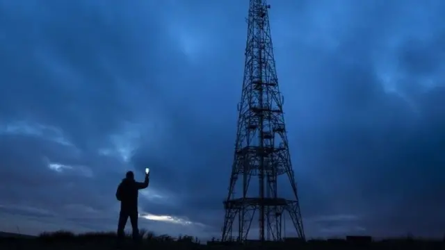человек с мобильным у мачты связи