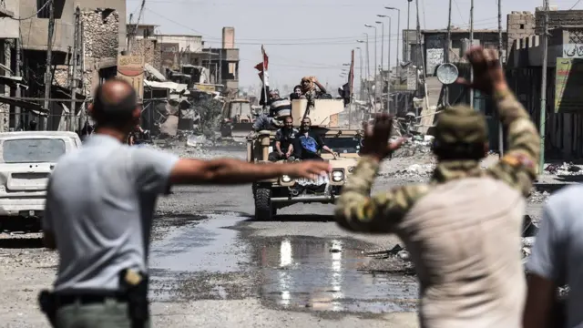 عراقيون فارون من القتال الدائر في مدينة الموصل القديمة يمتطون ظهر عربة مدرعة للقوات العراقية في الحي الصناعي للمدينة