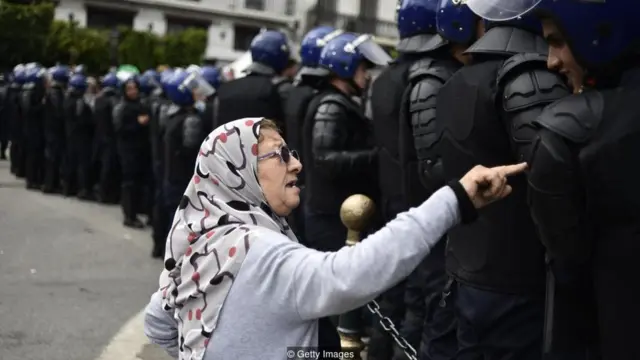 Uma senhora conversa com membros das forçassegurança durante os recentes protestos contra o governo na Argélia