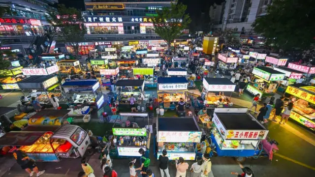 People are tasting food at the illuminated Longhu Zijin Night Market in Nanjing, China, on August 9, 2024.