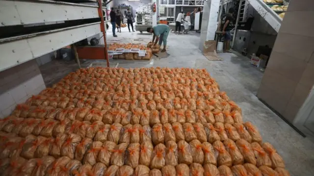 Para staf toko roti menyiapkan roti untuk warga Palestina yang mengantre di pintu perbatasan Rafah, pada 18 Oktober 2023.