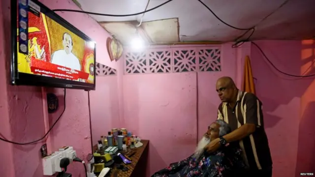 श्रीलंका के एक सैलून में राष्ट्रपति सिरीसेना का संबोधन सुनते लोग