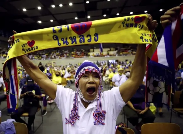 ผู้หญิงชูผ้าที่มีข้อความเรารักในหลวง