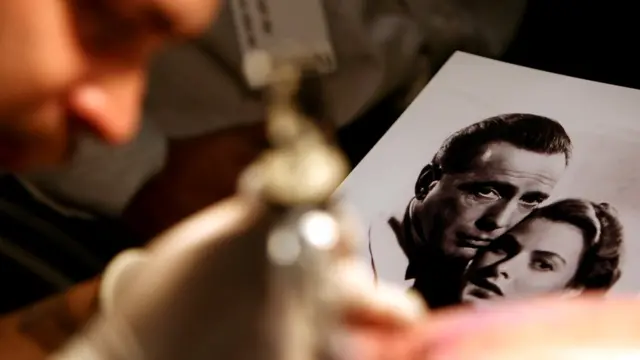 Мастер тату рисует на коже клиента сцену из "Касабланки". 15 сентября 2006 года, Лос-Анджелес