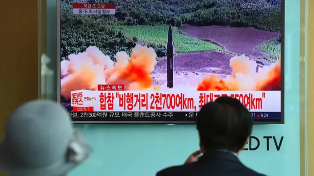 TOPSHOT - People watch a television news screen showing file footage of a North Korean missile launch, at a railway station in Seoul on August 29, 2017.