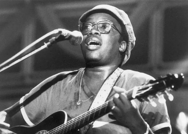 Milton cantando ao microfone e tocando violão