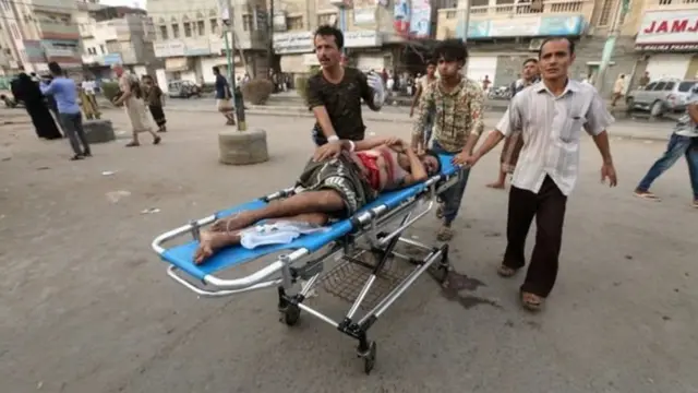 محاولة لإسعاف رجل أصيب في سوق الأسماك في إحدى الهجمات باليمن