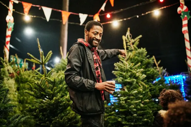 Smiling father shopping for Christmas tree with family