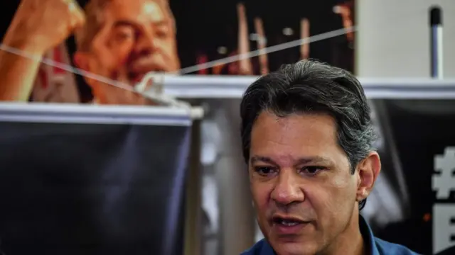 Haddad com posteraposta para amanha futebolLula ao fundo