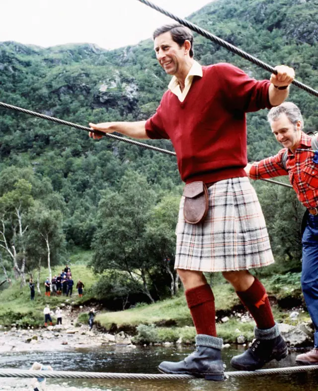 Sorrindo e usando trajes típicos escoceses, o príncipe Charles atravessa pontegusttavo lima casa de apostameio a trilha nos arredores da montanha Ben Nevis, na Escócia