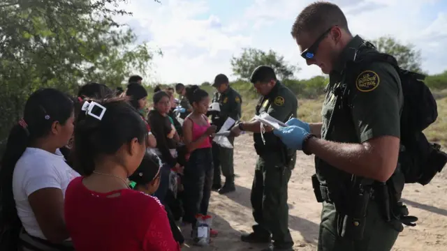 Inmigrantes junto a oficiales de frontera de Estados Unidos.