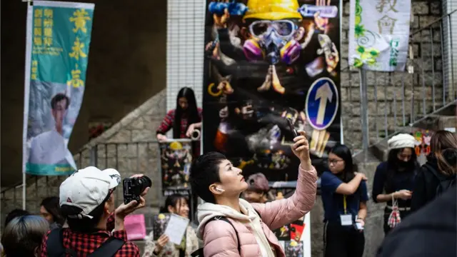 A woman taking picture of herself in front of a protest-related banner