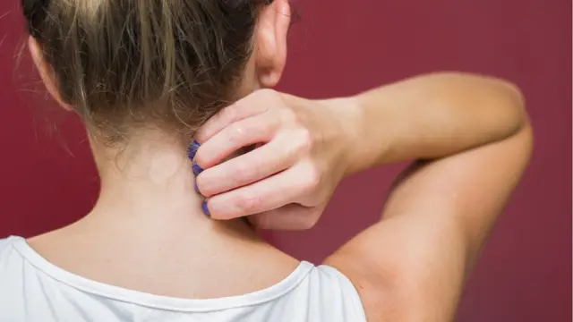 Mujer joven de espaldas rascándose.