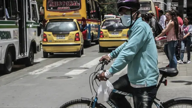 ਕੋਲੰਬੀਆ ਦੇ ਇੱਕ ਸ਼ਹਿਰ ਵਿੱਚ ਟ੍ਰੈਫਿਕ ਵਿੱਚੋਂ ਲੰਘਣ ਲਈ ਰਾਹ ਦੇਖਦਾ ਸਾਈਕਲ ਸਵਾਰ