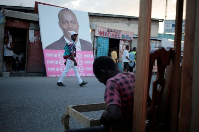 Un hombre camina frente a la pancarta electoral con la foto del candidato Jovenel Moïse en Puerto Príncipe.