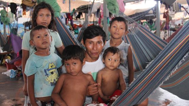 Indígena venezuelano Eulirio Baes sentado numa rede, cercado de cinco crianças de diferentes idades