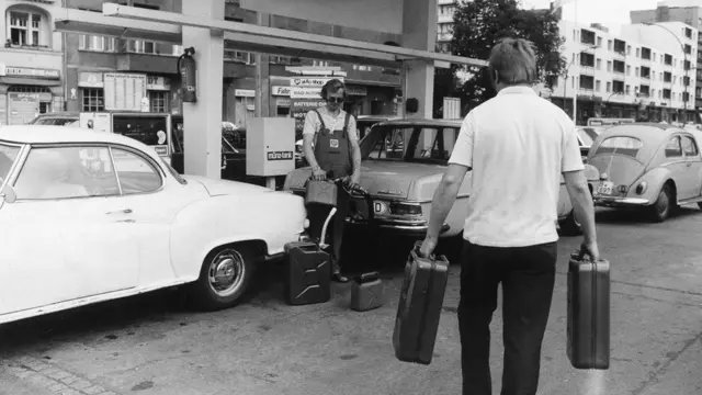 বার্লিনের একটি পাম্পে তেল জমিয়ে রাখতে ক্যান নিয়ে এসেছেন গাড়িচালকরা