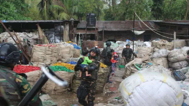 'জঙ্গি আস্তানা'য় আটকে পড়া এক শিশুকে বের করে আনছেন এক সেনা সদস্য।