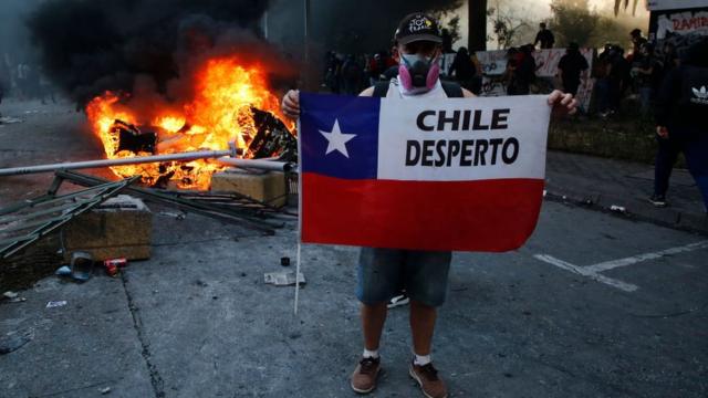 Un manifestante sostiene una bandera chilena con la frase "Chile despertó".