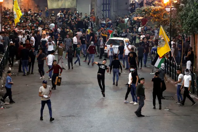 A Palestinian demonstrator hurls stones towards Israeli forces while others gather during an anti-Israel protest amid a flare-up of Israeli-Palestinian violence, in Hebron in the Israeli-occupied West Bank May 11, 2021.