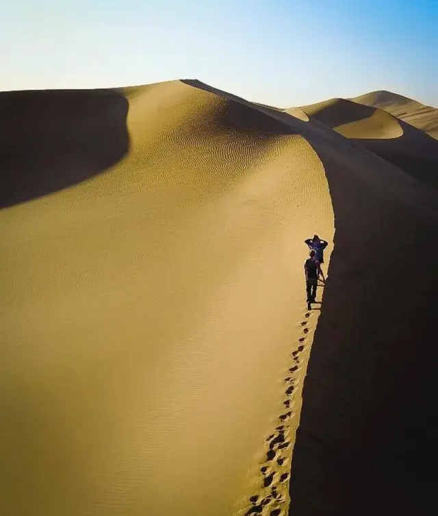 Dos personas caminando por una duna del desierto