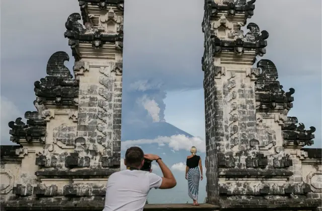 Una turista posa para una foto ante el volcán, en Datah, Karangasem.