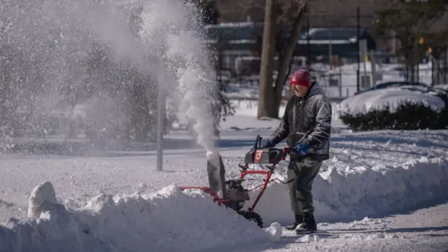 A man clears snow outside his home in New York