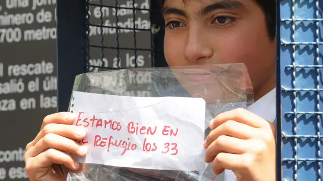 Estudiante con el mensaje "Estamos vivos los 33 en el refugio".