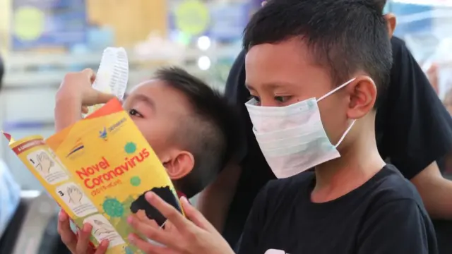Seorang anak membaca pamflet informasi tentang virus korona baru.